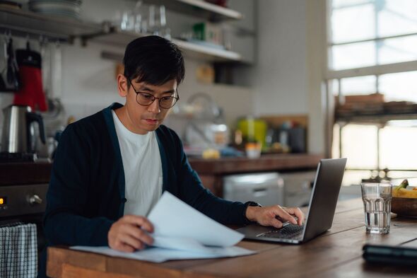 Young man going through bills with laptop