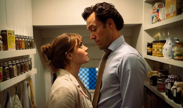 Woman and a man stand closely together in a cupboard.