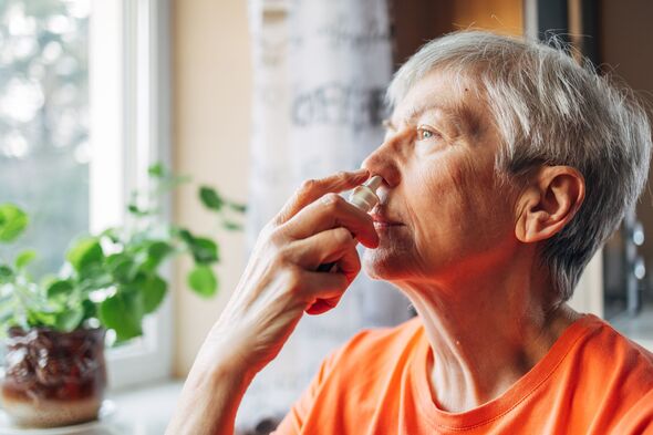 Senior woman using nasal spray at home