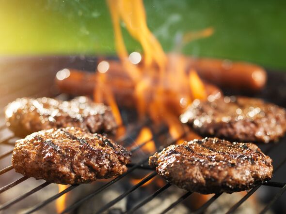 hamburgers and hotdogs cooking on flaming grill