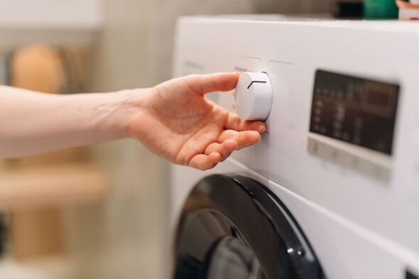 Woman adjusting washing machine program control dial in modern laundry