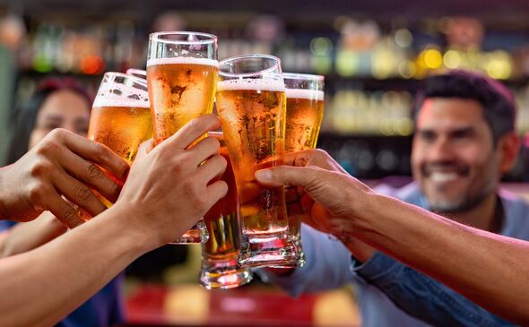 Group of friends making a toast while drinking beer at a sports bar