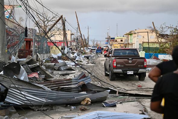 TOPSHOT - A car drives through the a destroyed neighborood following the passage of Hurricane Melissa, in Black River, Jamaica o