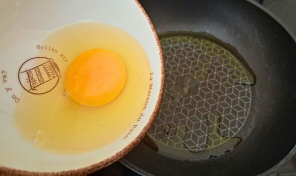 Picture of a egg being added to a frying pan