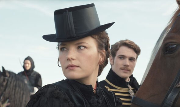 A woman in a black hat looks serious