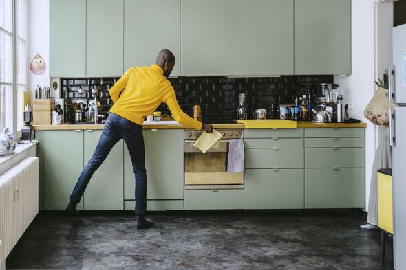 Full length of mid adult man doing chores in kitchen at home