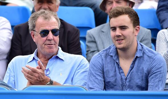 Two men in blue shirts sit as part of an audience as one of the men claps