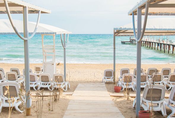 Empty luxury beach resort with white sun loungers cabanas near turquoise sea shoreline, capturing authentic vacation mood, summer tourism, relaxation, hospitality, seaside escape concept