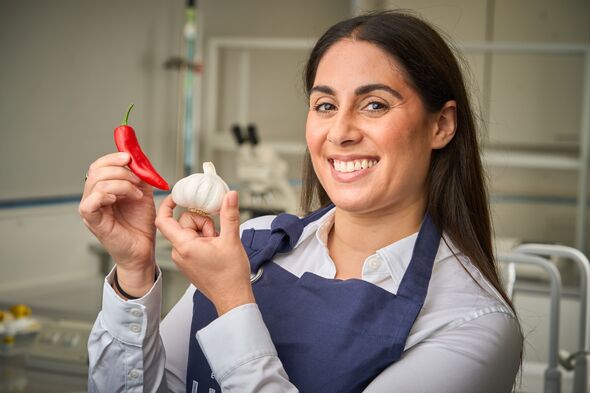 Natalie Alibrandi holds a chilli pepper and bulb of garlic