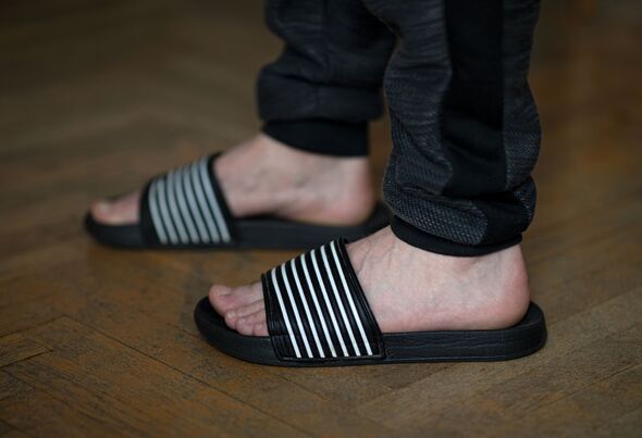 Closeup of male feet in flip flops at home on the wooden floor