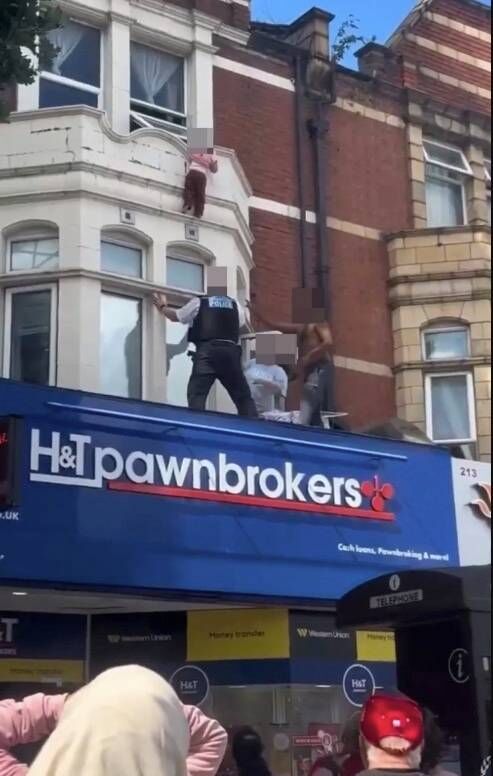 Heart-stopping moment terrified child clings to window ledge above high street shop before falling as crowd watches on