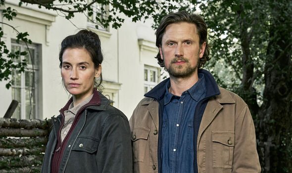 A woman and a man stand by a true outside a house