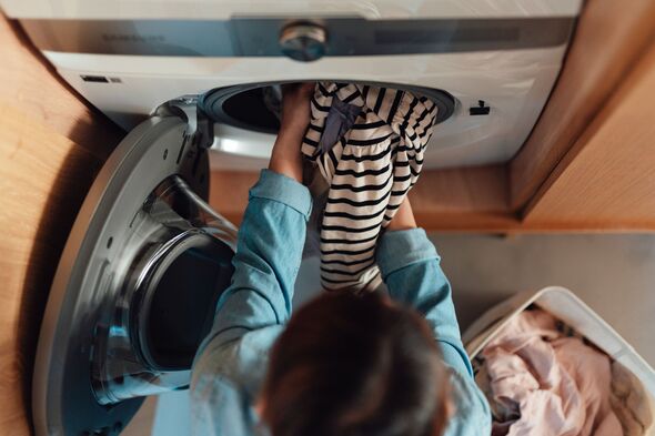 Overhead of young woman loading washing machine