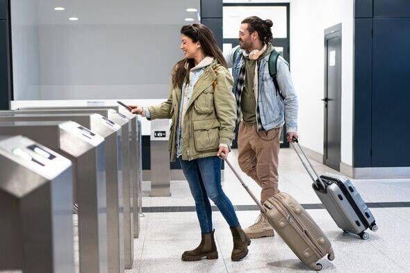 Tourists passing through airport security gates with suitcases and backpacks