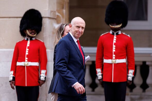 John Healey walks past soldiers in bearskins