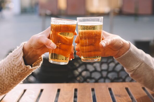 Close-up of two people toasting with pint glasses