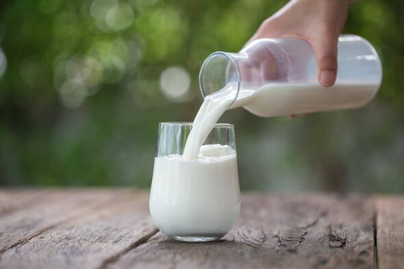 Pouring milk in the glass, background of nature