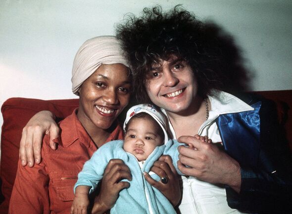 Close up of Gloria Jones and Marc Bolan who smile and lean into each other as they hold their son Rolan in front of them