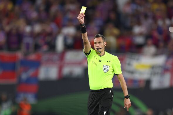 Referee Maurizio Mariani shows a yellow card