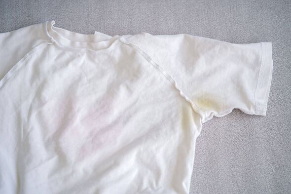 A yellow spot on a white T-shirt. Top view.