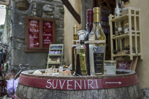 Bottles of domestic liqueurs displayed on a wooden barrel in front of a souvenir shop