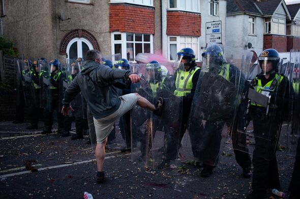 A man is seen kicking riot police as violent clashes erupt