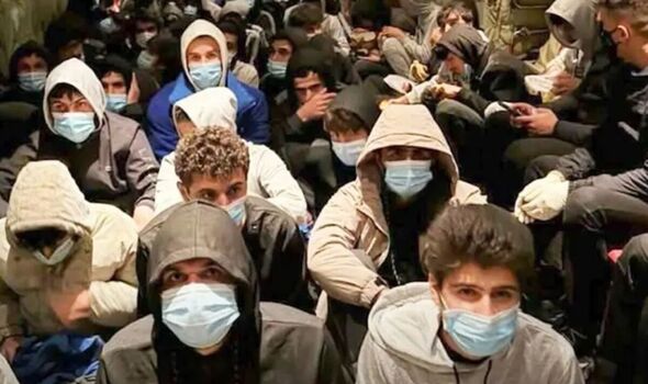 Scores of migrants seated on a floor and wearing face masks during their captivity in Libya
