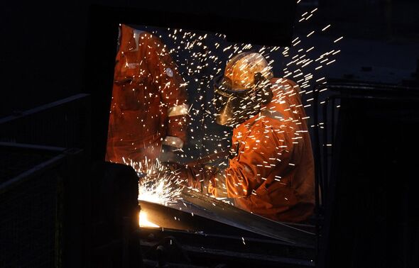 Steel worker in factory behind wall of sparks