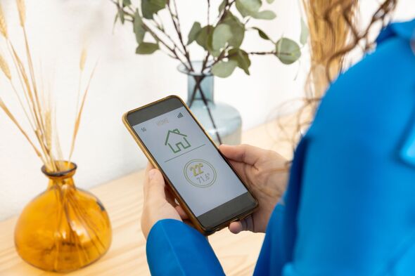 Close-up view of woman controlling home heating from her smart phone.